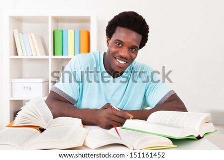 Young African Man Studying At Home With A Lot Of Books
