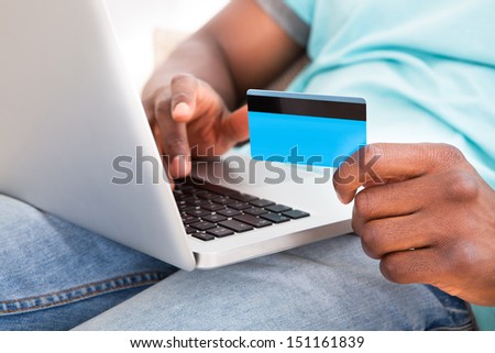 Happy Young African Man Using Laptop Sitting On Couch At Home
