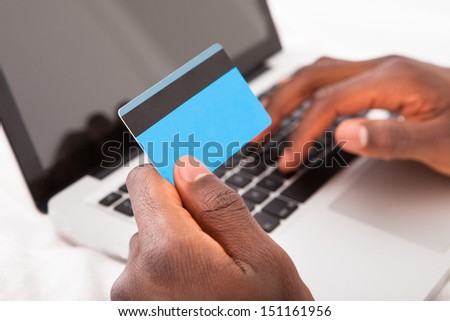 Young African Man Holding Credit Card And Using Laptop For Online Shopping