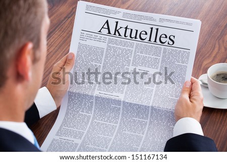 Businessman Reading Newspaper With The Headline Current News