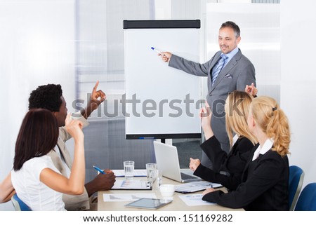 Businesspeople Looking At Businessman Explaining In Presentation