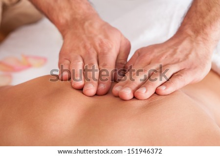 Beautiful young woman getting back massage at spa