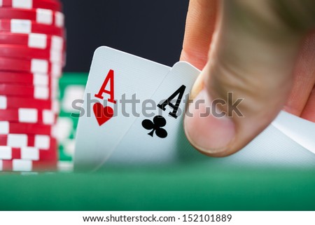Close-up of male poker player lifting the corners of two cards