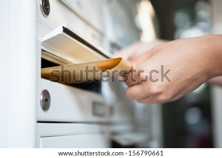 Close-Up Of Woman\'S Hand Holding Envelope And Inserting In Mailbox