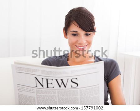 Young Happy Woman Reading Newspaper On Couch