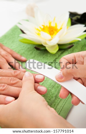 Close-up Of Beautician Hand Filing The Nails Of Woman In Salon