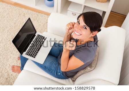 Excited Young Woman Sitting With Laptop On Couch
