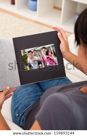 Close-up Of Woman Looking Through Photo Album; Indoors