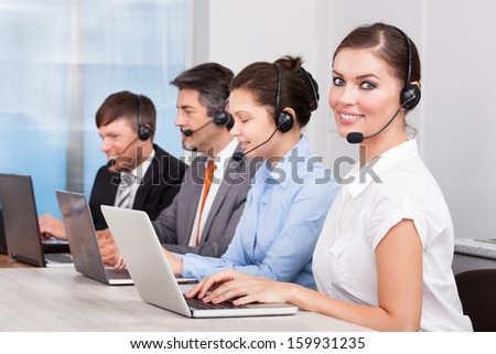 Call center operator sitting in row working at office