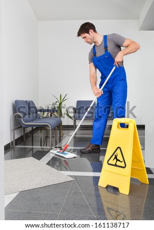 Portrait Of Young Man Cleaning The Floor With Mop In Office