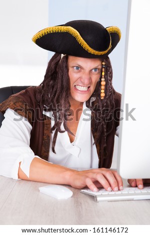 Portrait Of A Angry Pirate Clenching His Teeth Using Computer