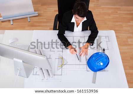 Young Happy Female Architect Working On Blue Print In Office