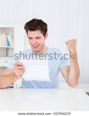 Happy Young Man Reading Paper Holding In Hands