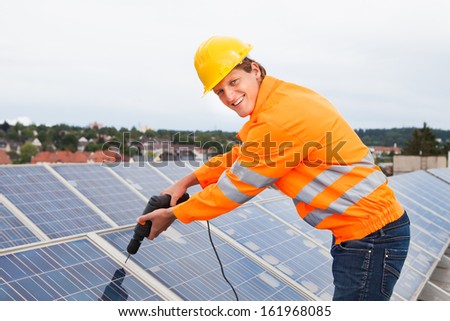 Male Engineer Fixing Solar Panels With Drill Machine