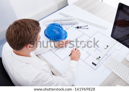 Portrait Of A Young Architect Drawing Plan On Blueprint