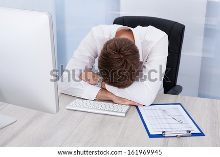 Portrait Of Young Tired Businessman Sitting In Office