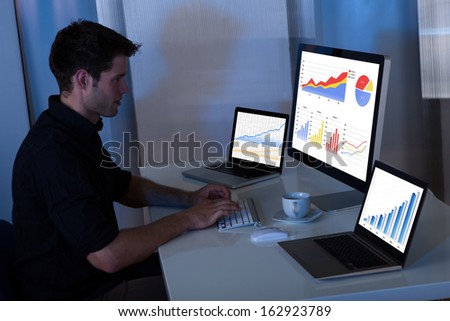 Young man working at computer in the office at night
