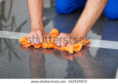 Young Man Cleaning The Dust On Floor With Duster