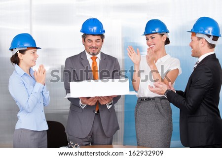 Happy Coworkers Applauding For A Architect Holding Architectural Model