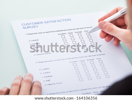 Close-up Of Man\'s Hand Filling Customer Survey Form