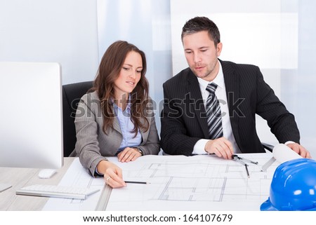 Two Architect Looking At Blue Print Discussing Together