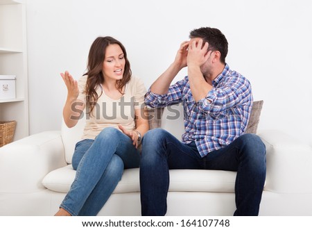Portrait Of Frustrated Couple Sitting On Couch Quarreling With Each Other