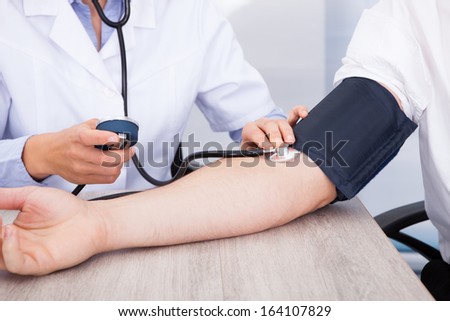 Close-up Of Female Doctor\'s Hand Checking Blood Pressure