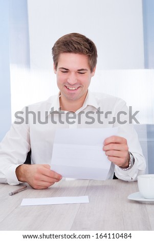 Portrait Of Happy Young Businessman Reading Paper Holding In Hand