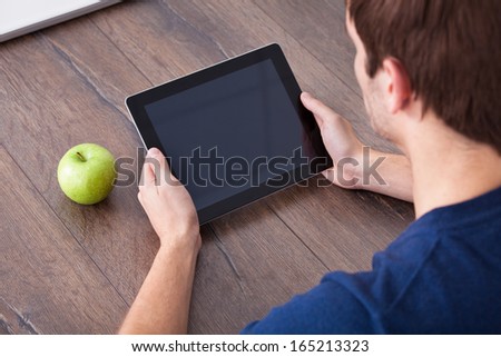 Close-up Of Person\'s Hand Holding Digital Tablet With Green Apple On Desk