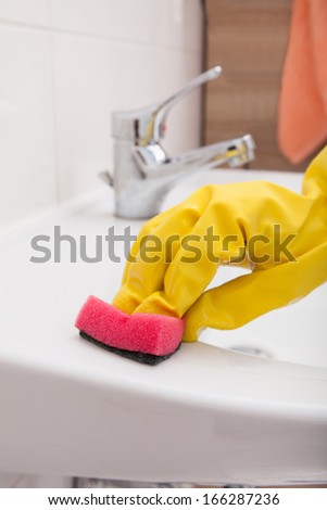 Close-up Of Hand With Gloves Cleaning Sink
