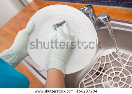 Close-up Of A Woman\'s Hand Washing Dish In Kitchen Sink