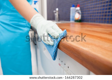 Closeup Of Young Woman Wearing Apron Cleaning Kitchen Worktop