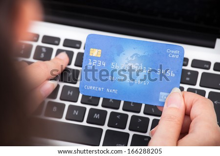 Close-up Of A Person Holding Credit Card Using Laptop