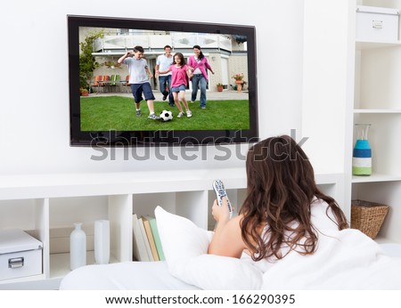 Portrait Of Young Woman Sitting On Couch Watching Television