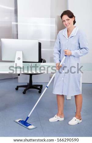 Portrait Of Happy Female Janitor Cleaning Floor At Office