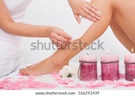 Beautician Waxing A Woman\'S Leg Applying Wax Strip