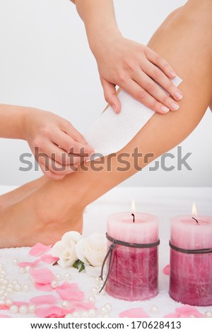 Beautician Waxing A Woman\'s Leg Applying Wax Strip