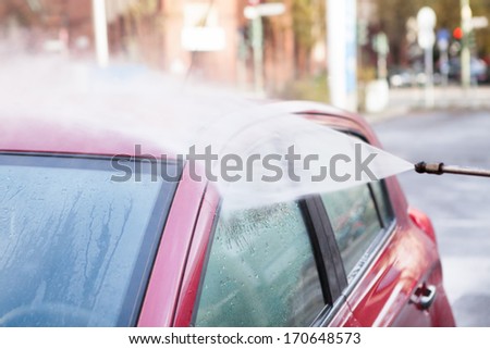 Hose Spraying Water On Red Stylish Car