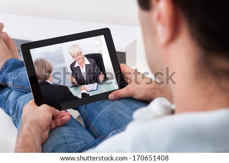 Close-Up Of Young Man Watching Movie On Tablet Pc