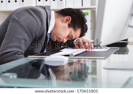 Portrait Of A Young Tired Businessman Sleeping At Desk