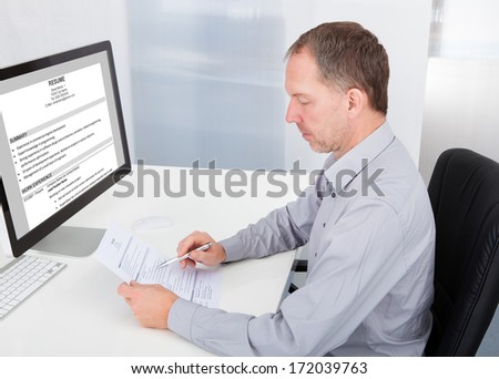 Portrait Of Mature Businessman Reading Resume In Office