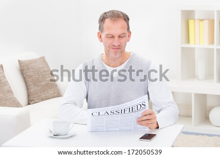 Mature Man Reading Newspaper While Having Coffee