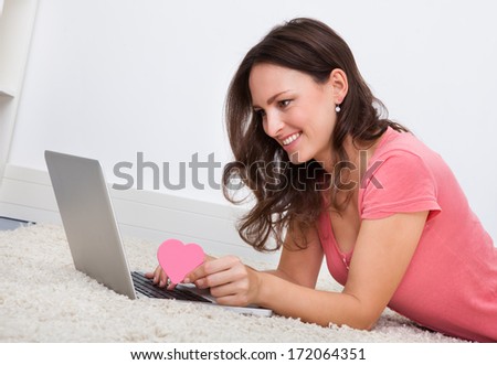 Portrait Of Smiling Young Woman Lying On Floor In Front Of Laptop