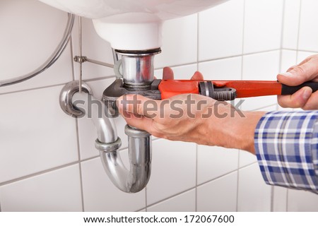 Close-Up Of Male Plumber Fitting Sink Pipe In Bathroom