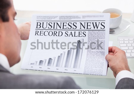 Close-up Of Young Businessman Reading News On Newspaper