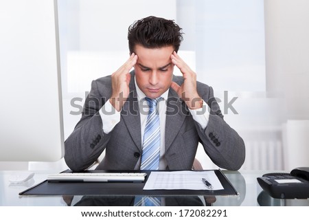 Portrait Of A Stressed Businessman Sitting At Desk