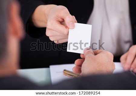 Close-up Of Businesswoman Exchanging Visiting Card With Businessman