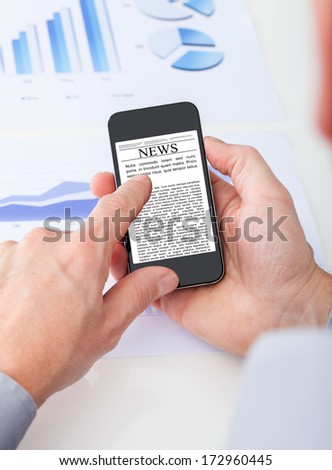 Close-up Of Person's Hand Reading News On Cell Phone