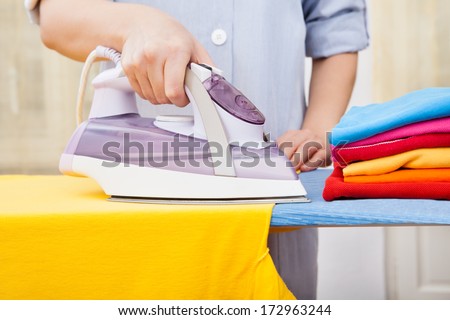 Close-up Of Maid Ironing Clothes On Ironing Board