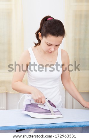 Portrait Of A Young Woman Ironing On Ironing Board